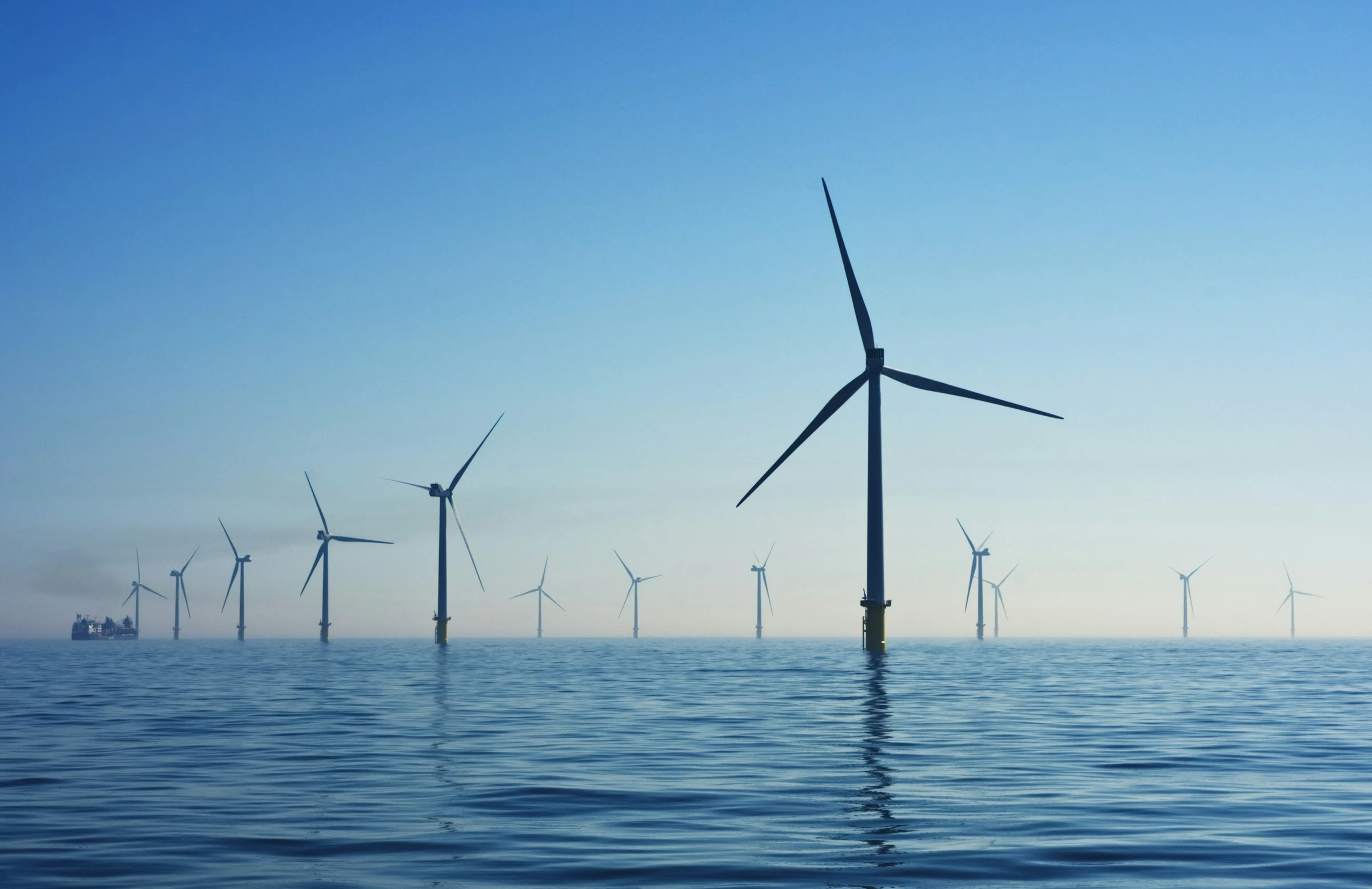 Offshore wind turbines across a blue sea; illustrative renewable energy photography